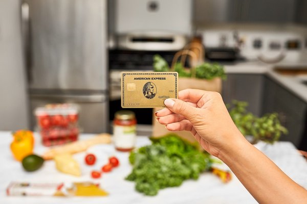 Person holding up an American Express card inside a kitchen.
