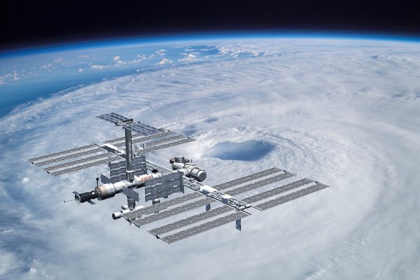 the international space station floating in orbit over clouds.