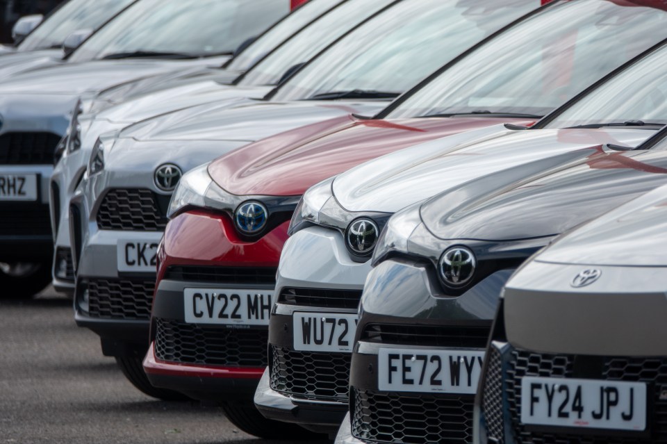 Row of new and used Toyota cars for sale at a dealership.