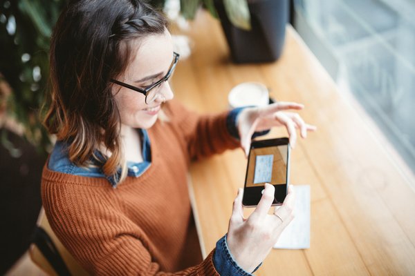 Adult smiles while using smartphone to deposit a paycheck.