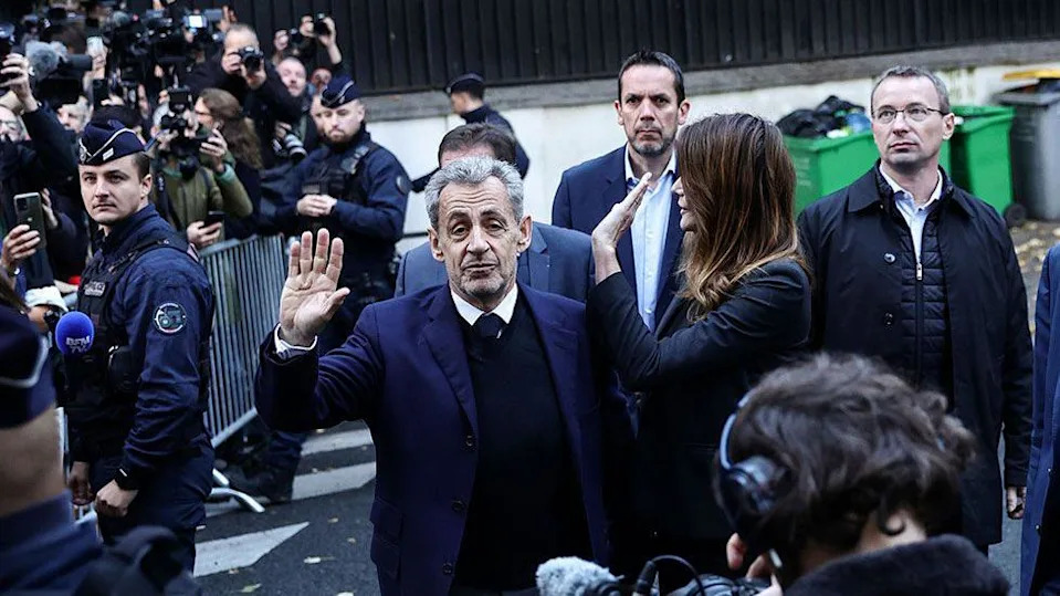 Former French President Nicolas Sarkozy and his wife wave at crowds and photographers on the street before he goes to prison
