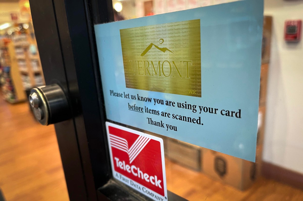 A Vermont WIC card notice on a store door asks customers to inform staff before items are scanned. Below it is a TeleCheck sticker. Store interior is visible through the glass.