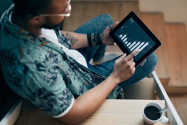 Person sitting on staircase is looking at stock chart on a tablet.