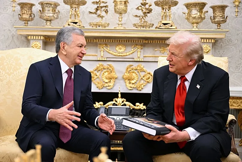 Uzbekistan's President Shavkat Mirziyoyev hands Donald Trump a book as they meet in the Oval Office at the White House, Washington, Thursday, 6 Nov. 2025