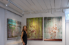 Miranda Donovan standing in her London studio beside three mixed-media paintings