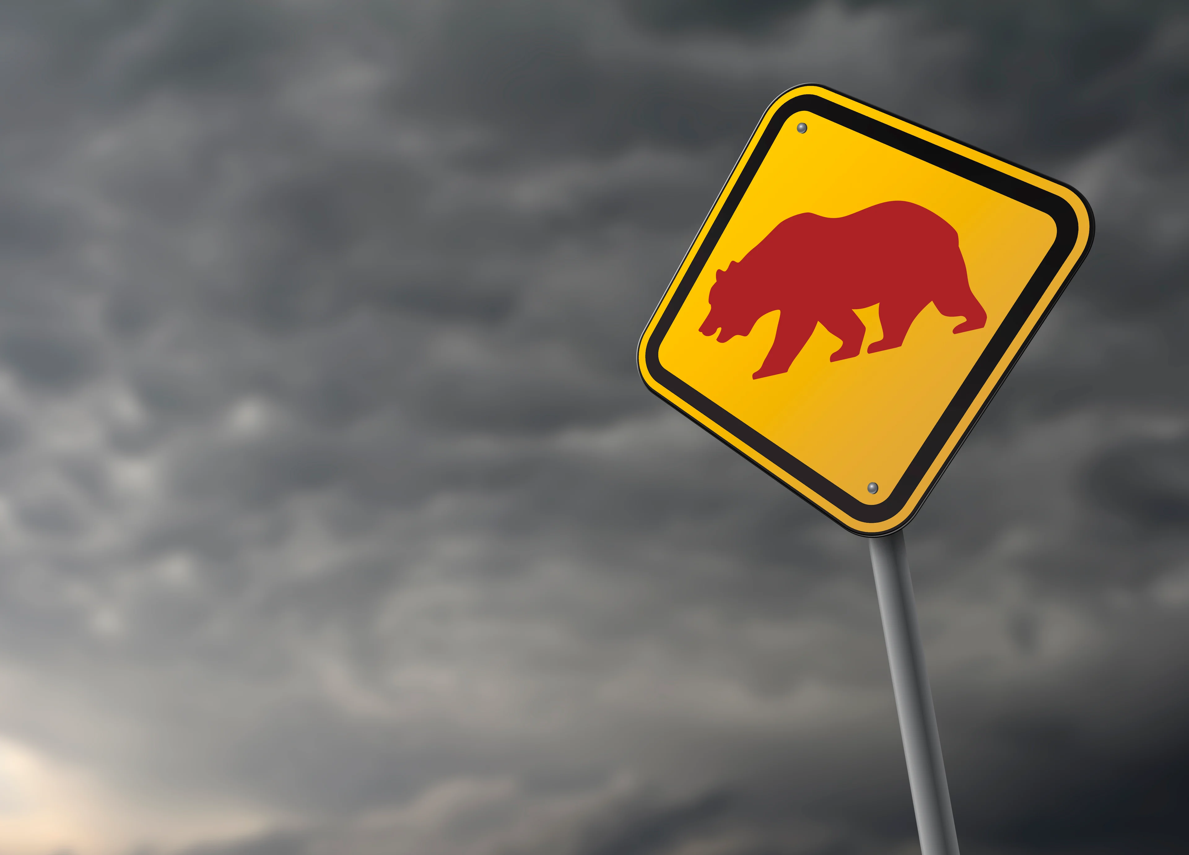 Sign with a bear on it against a stormy sky.