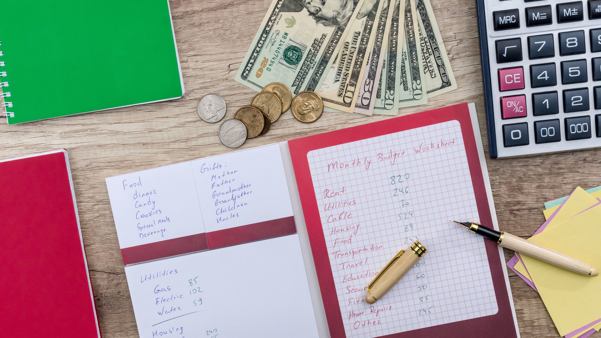 A monthly budget notebooks open lying on a wooden desk.